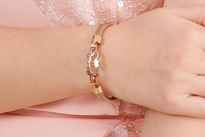 Close-up of rose gold mesh bracelet featuring a hollow MOM heart design on a model
