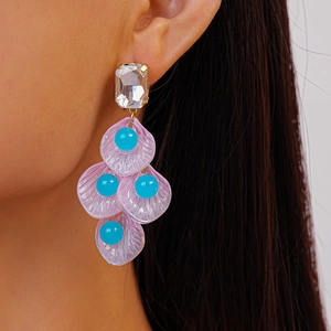 Détails de boucles d'oreilles à pétales violets, perles bleues et cristal sur un mannequin