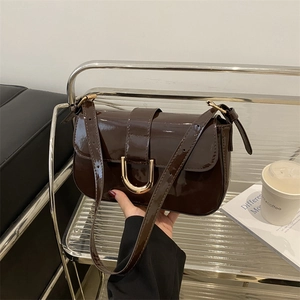Brown patent leather shoulder bag with gold horseshoe buckle and adjustable strap