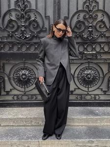 Dettaglio di un blazer a quadri grigio scuro abbinato a pantaloni larghi e mocassini