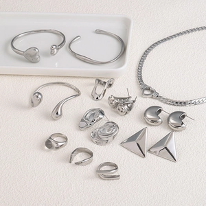 Polished stainless steel jewelry set including heart ring, earrings and bracelet on white tray