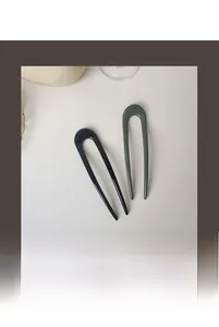 Close-up of minimalist U-shaped resin hair pins in dark blue and greyish green gloss finish