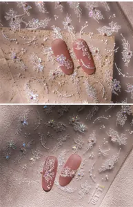 Macro shot of white floral lace nail art stickers with delicate 3D pearl decorations
