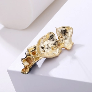 Back view of minimalist gold mask brooch showing metal texture and pin safety closure