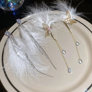 Detailed view of silver and gold tassel earrings with butterfly charms on white porcelain