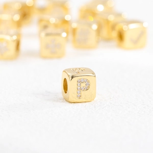 Macro view of 18k gold plated cube bead with letter P and cubic zirconia inlay