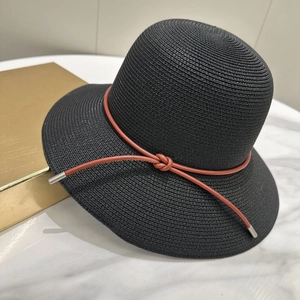 Vue détaillée d'un chapeau de paille noir avec cordon en cuir brun et embouts métal
