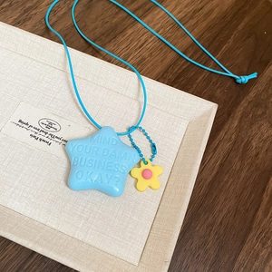 Dettaglio del ciondolo a stella blu inciso con fiore giallo su cordoncino azzurro morbido