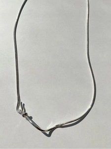 Detail shot of a minimalist 925 sterling silver snake chain with artistic knot pendant