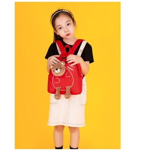 Detail of red toddler backpack with 3D brown teddy bear and happy text on yellow backdrop