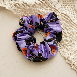 Close-up of satin Halloween scrunchie with haunted house and pumpkin patterns