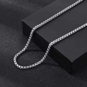 Detailed view of a silver stainless steel box chain necklace on a black presentation box