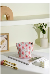 Close-up of floral knit makeup bag with gold flower zipper and H&R logo label