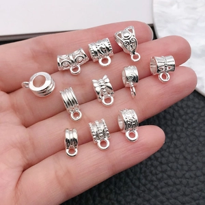 Silver alloy DIY bail beads and connectors for necklaces shown on a hand for scale