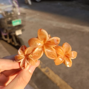 Detail of amber orange floral hair claw clip with matte finish in natural light