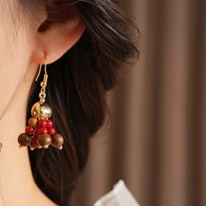 Close-up of bohemian earrings with red glass beads and brown wooden tassels on a model
