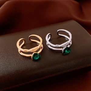 Detail eines 18K vergoldeten Doppelrings mit grünem Dreieckskristall und Pavé-Besatz