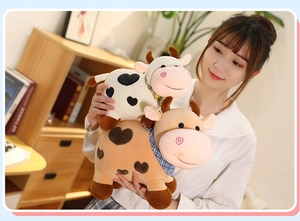 Primer plano de dos vacas de peluche con dibujos de corazones y bufandas de cuadros
