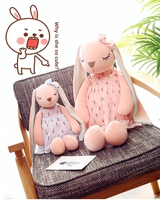 Detail of two plush bunny dolls in floral dresses sitting on a wooden armchair