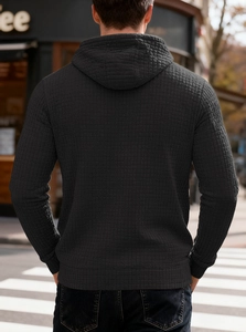 Detail view of the waffle texture and ribbed hem on a dark grey hooded sweatshirt for men