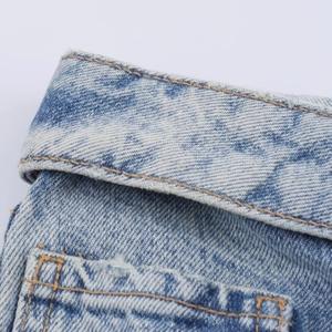 Détail de denim bleu clair délavé avec surpiqûres gingembre et décoration de déchirures