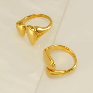 Polished 18k gold minimalist open ring with heart design on warm stone background