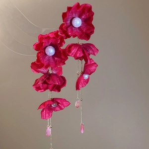 Detail of red fabric flower earrings with crystal tassel and pearl accents in macro view