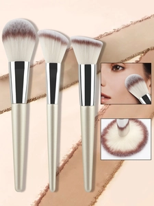 Detailed close-up of champagne makeup brush set with soft synthetic bristles and golden handles