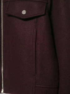 Detailed macro shot of dark purple wool jacket featuring metal zipper and snap button pockets