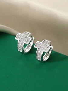 Macro shot of silver cross earrings with shimmering zircon stones and huggie closure