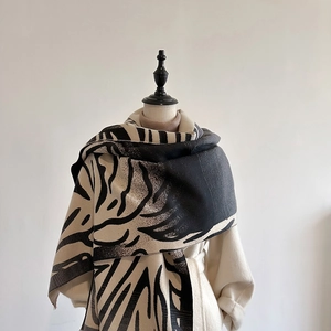 Detailed close-up of tiger pattern knit scarf draped on a mannequin with a beige coat