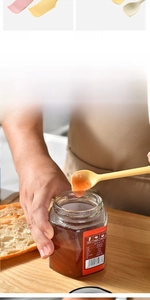 Detailed view of yellow silicone spatula scooping fruit jam from a jar in kitchen