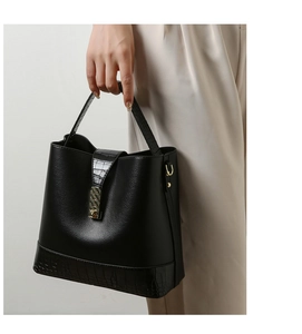 Detail of black pebbled leather bucket bag with crocodile texture and gold clasp