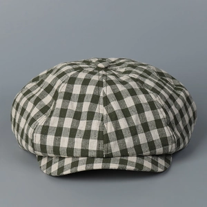 Detailed view of green gingham pattern fabric and top button on a retro newsboy cap