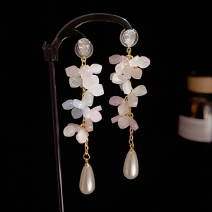 Vue détaillée de boucles d'oreilles dorées à pampilles, pétales roses et perles blanches