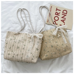 Detail of straw tote bags with floral embroidery, lace bows, and cotton rope handles