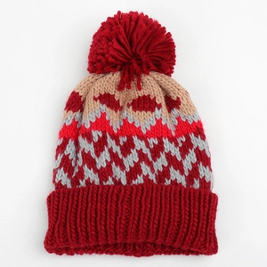 Detailed view of winter knit beanie showing colorful geometric jacquard and thick red pom-pom