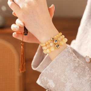 Detailed view of layered citrine beaded bracelets with elegant golden charms on wrist