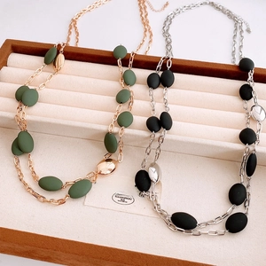 Detail of double-layer chain necklace with matte beads in gold green and silver black