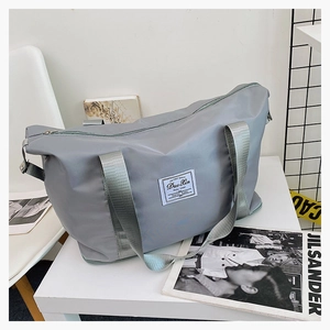Detail of grey waterproof nylon travel bag showing woven handles and front label