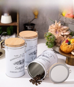 Detail of three white tinplate canisters with wooden lids and metal buckles for coffee and sugar