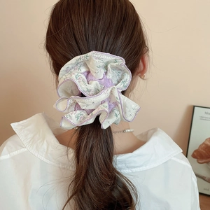 Detail of floral scrunchie with lace trim styled in a ponytail on a model