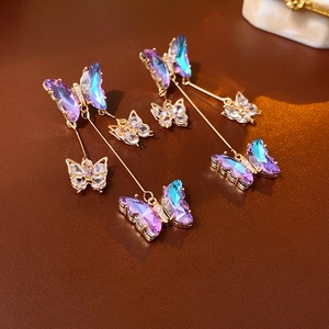 Close-up of purple butterfly tassel earrings with gradient wings and crystal accents