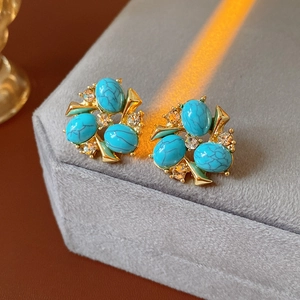 Gros plan de boucles d'oreilles vintage fleurs avec turquoises et zircons sur coffret