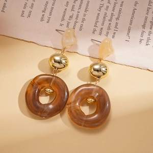 Detail of vintage acrylic drop earrings with amber texture and gold beads on a book