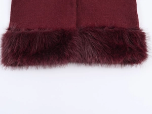 Détail de la bordure en fausse fourrure bordeaux sur un vêtement en tricot et couture