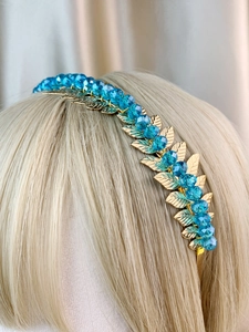 Detailed close-up of golden leaf headband with blue crystal beads on a mannequin head