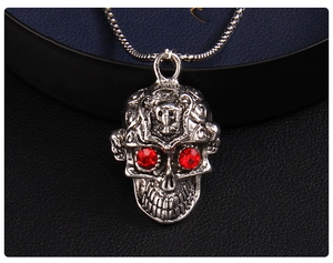Gros plan détaillé d'un pendentif tête de mort punk argenté avec des yeux en strass rouges