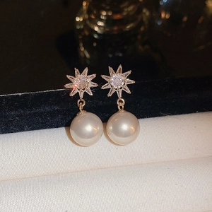 Macro shot of gold-plated starburst earrings with sparkling cubic zirconia and white pearls