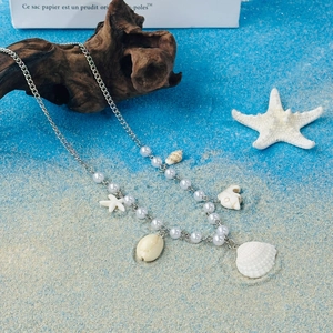 Detail view of seaside necklace with pearls and shell pendants on rustic driftwood